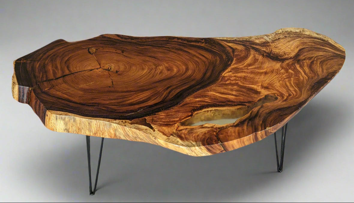 Wooden coffee table with a black metal base in front of a black leather sofa.