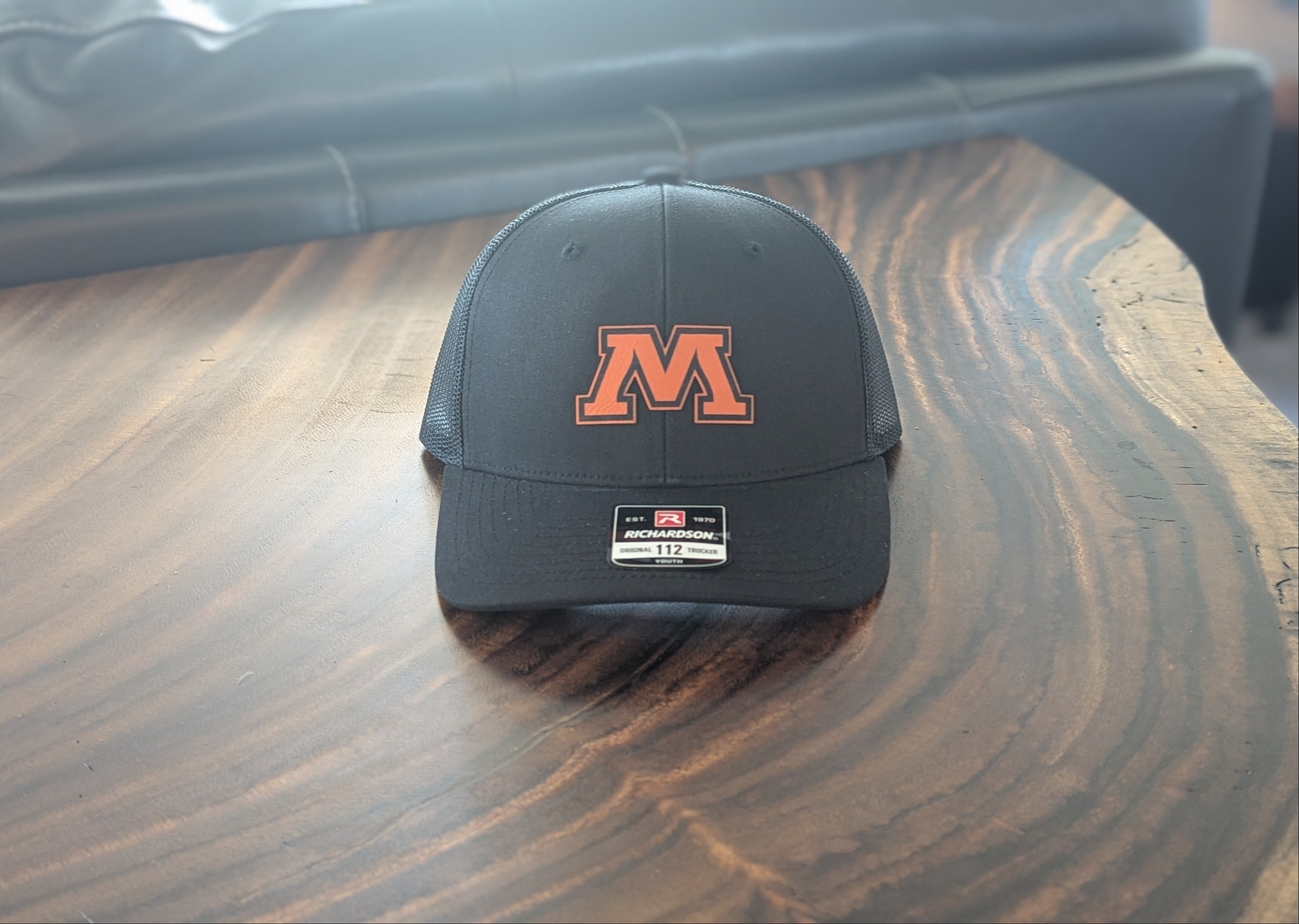Black cap with orange logo on a wooden table